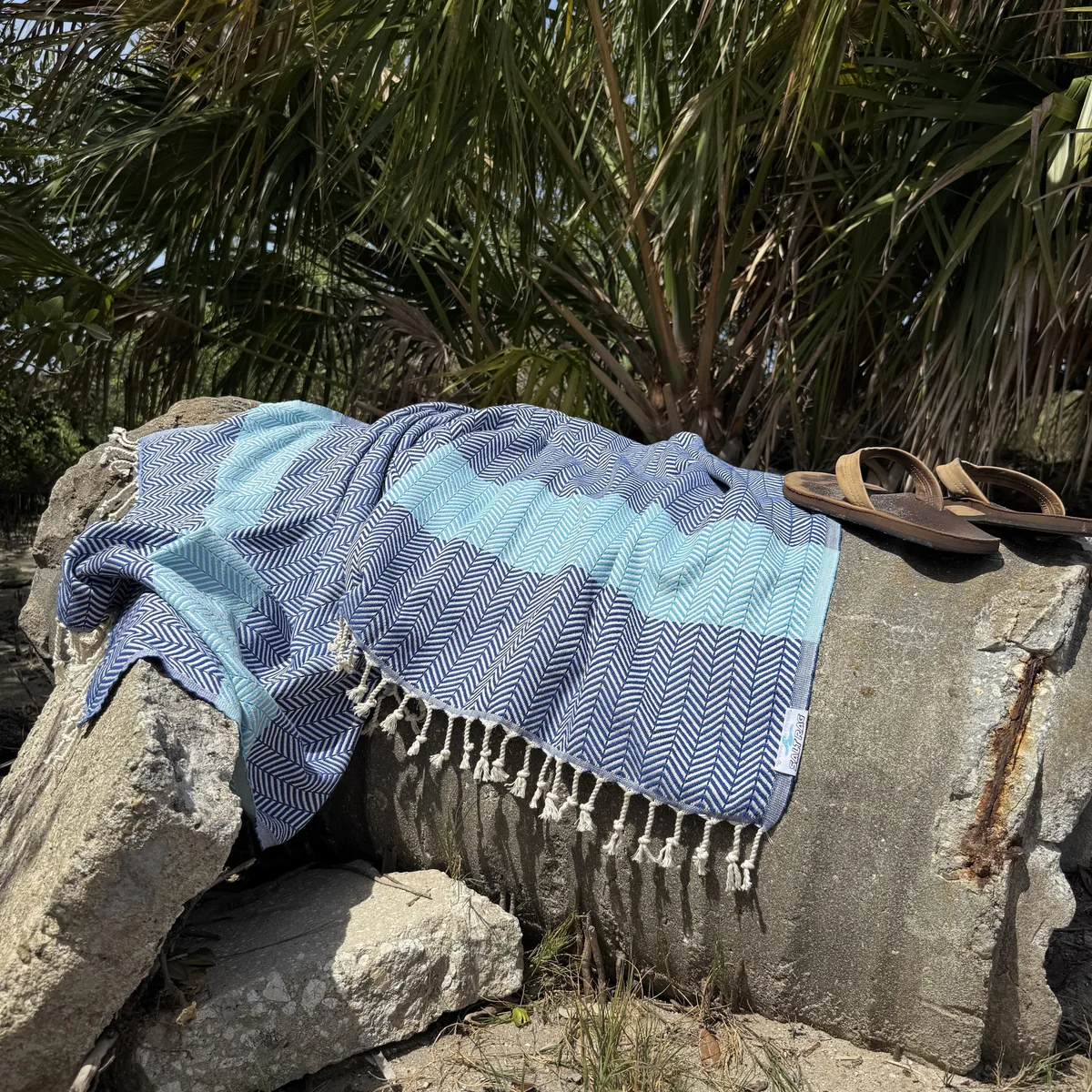 Blue patterned Rag spread on rocks with sandals.