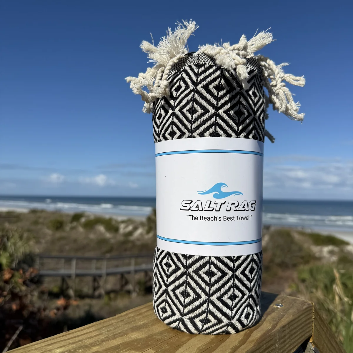 Black-and-white rolled Salt Rag with full fringe on a coastal deck.