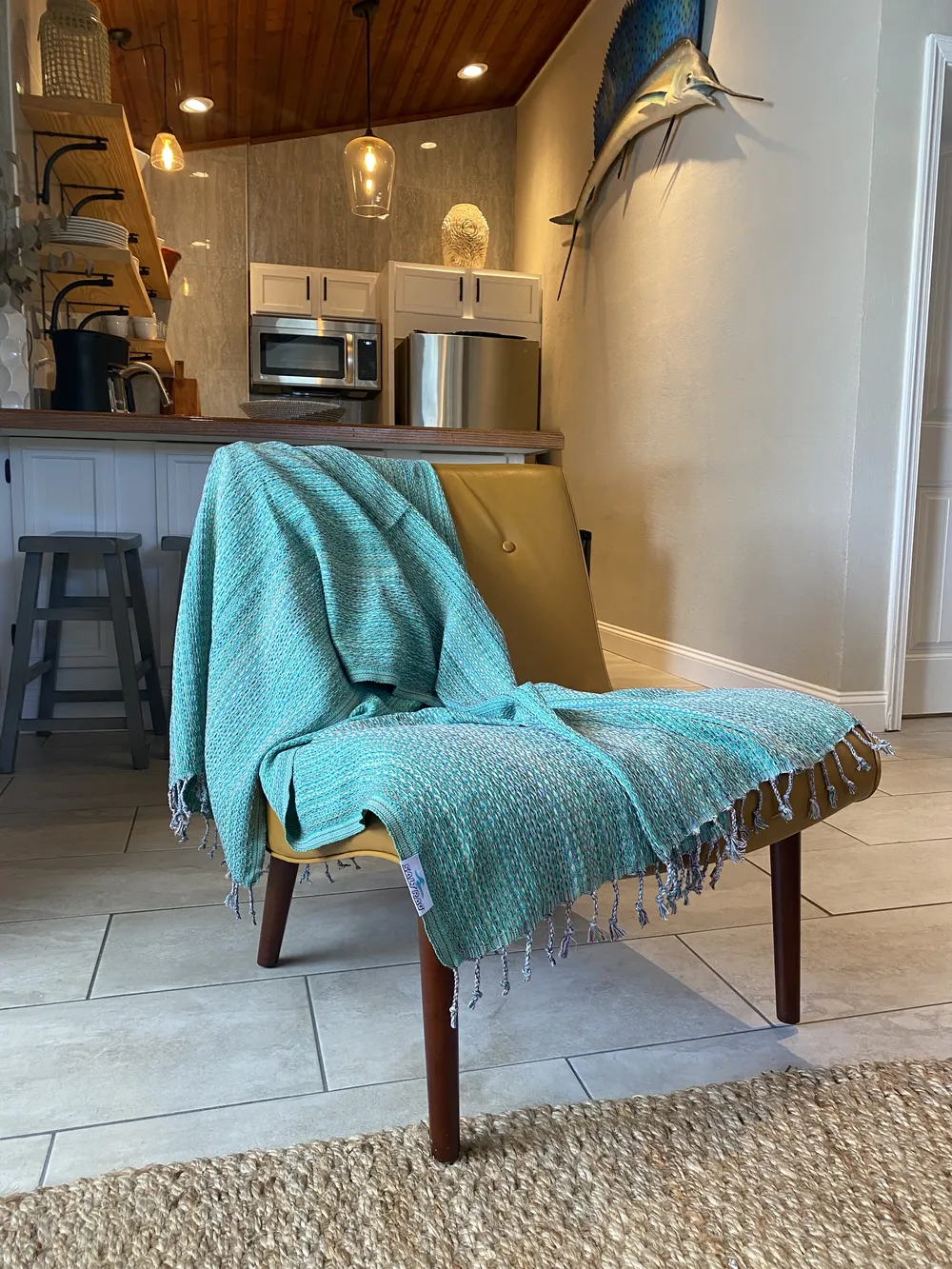 Teal handloomed Salt Rag with fringe draped over a mustard chair in a kitchen.
