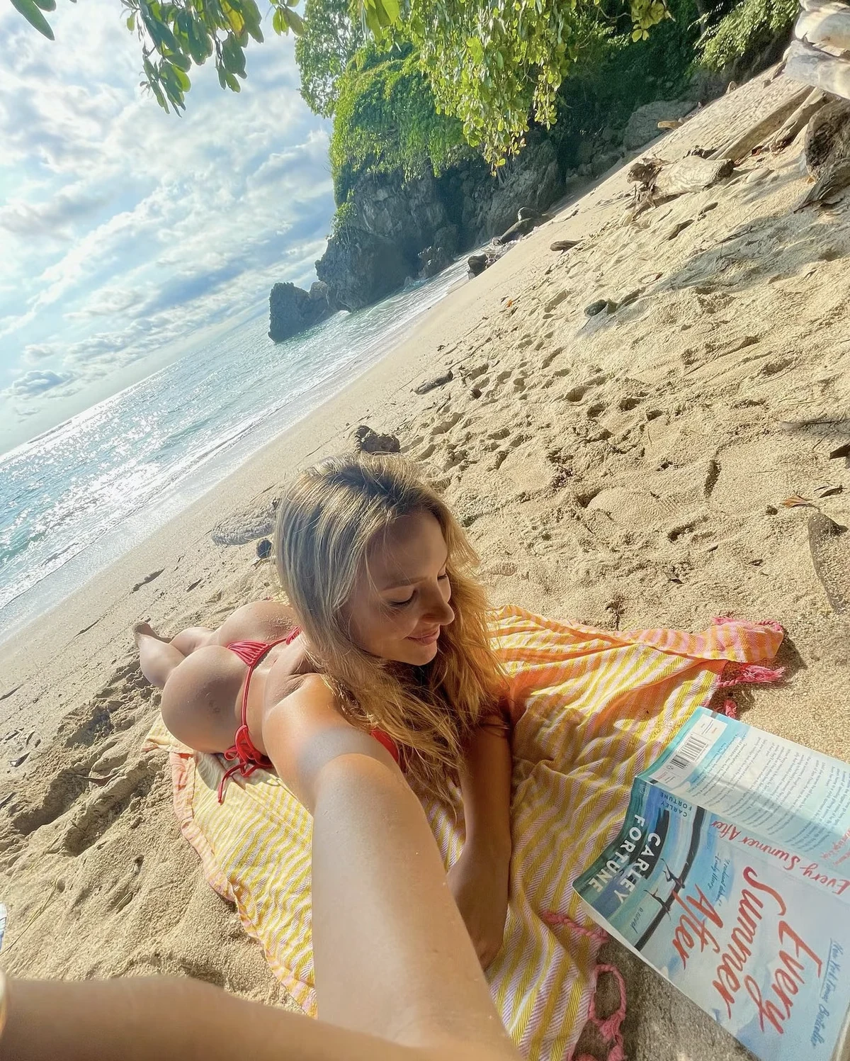 A person reading on the beach with a Salt Rag draped around their shoulders.
