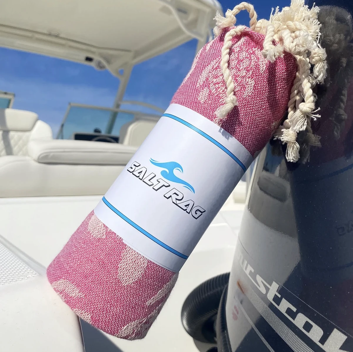 A rolled pink Salt Rag leaning against a boat’s outboard motor.