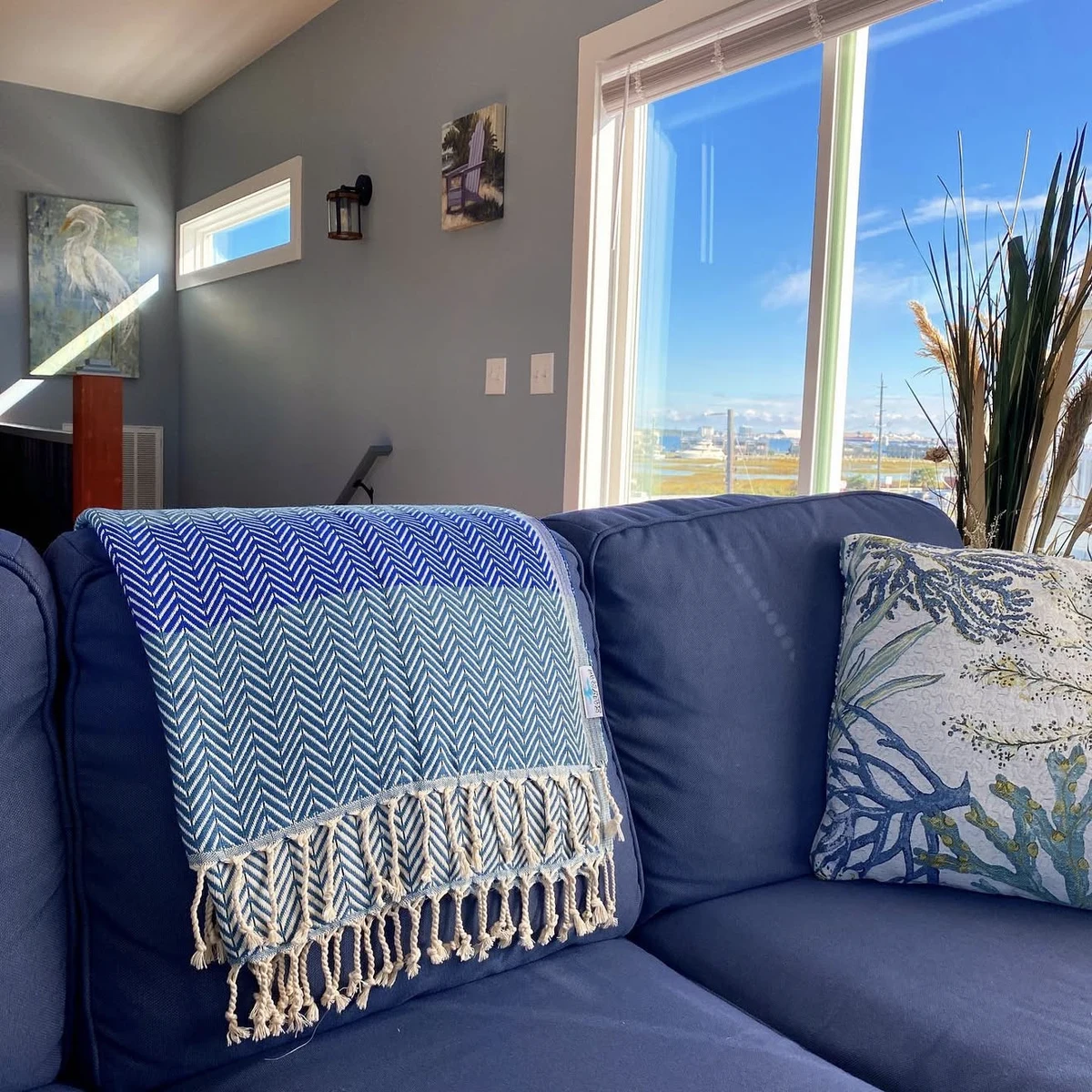 A blue and pale teal Salt Rag draped over a blue sofa beside a sunny window.