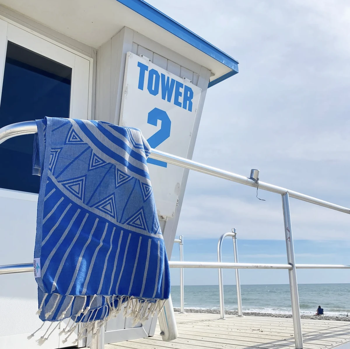 A blue patterned Salt Rag hanging from a beach lifeguard tower.