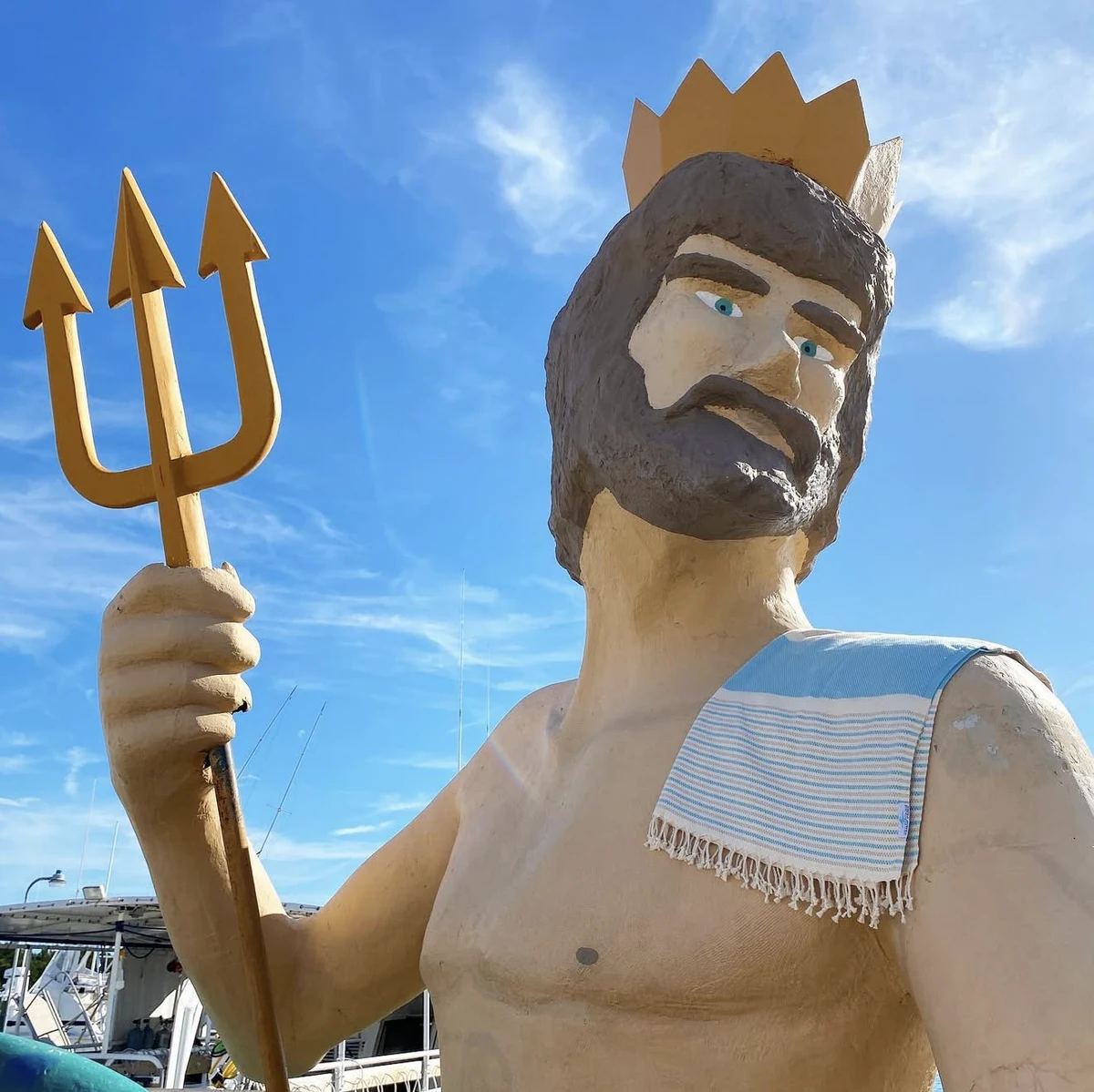 A striped Salt Rag draped over the shoulder of a King Neptune statue at a marina.