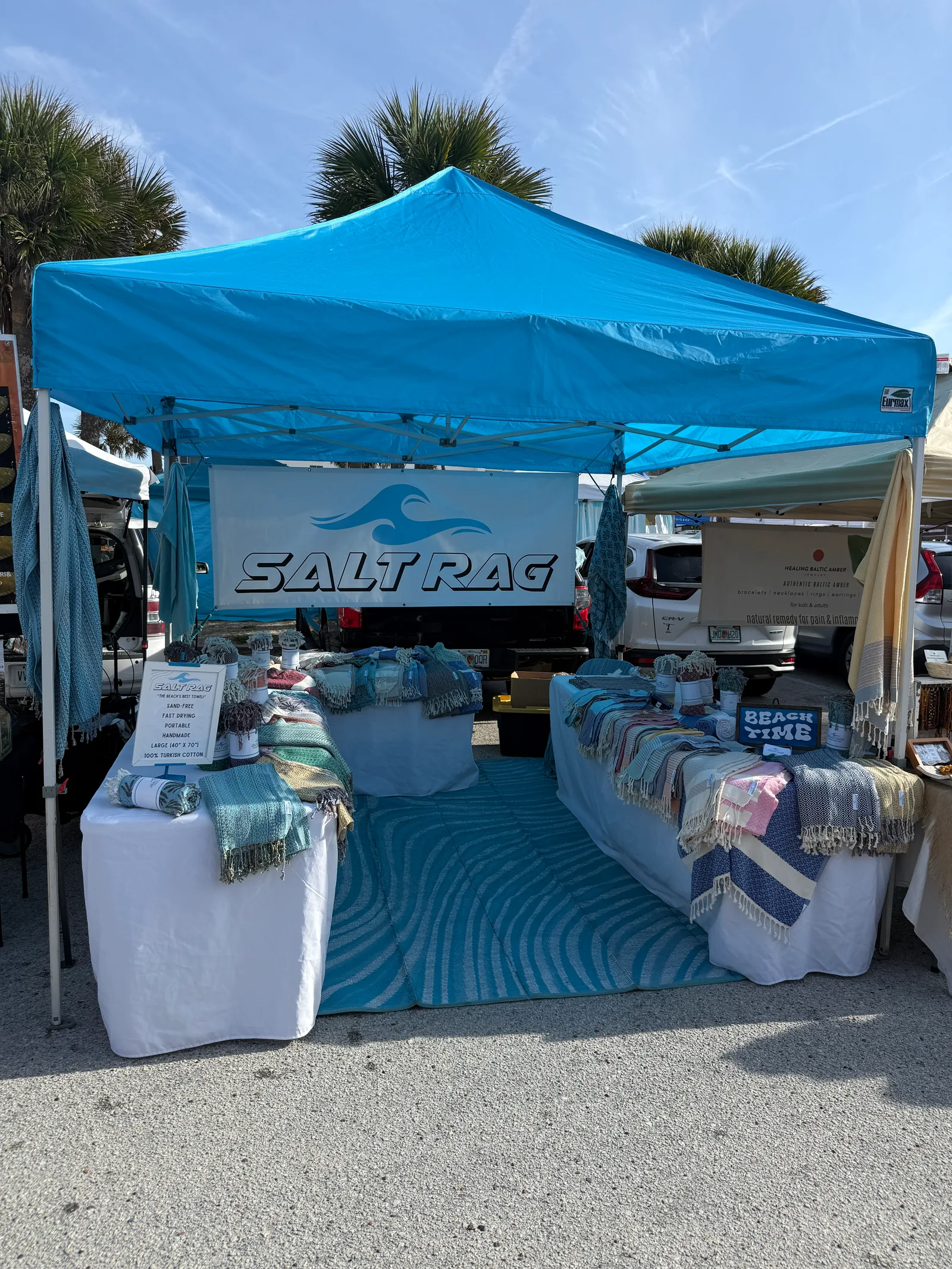 Salt Rag's blue canopy and banner above tables of folded, rolled and draped Rags.