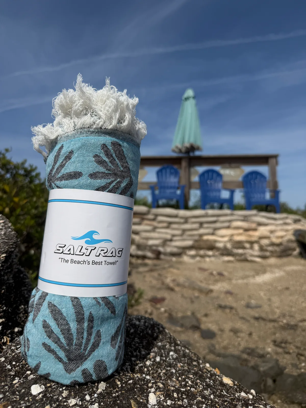 A rolled pale green Salt Rag with its woven label and knotted cream fringe visible.