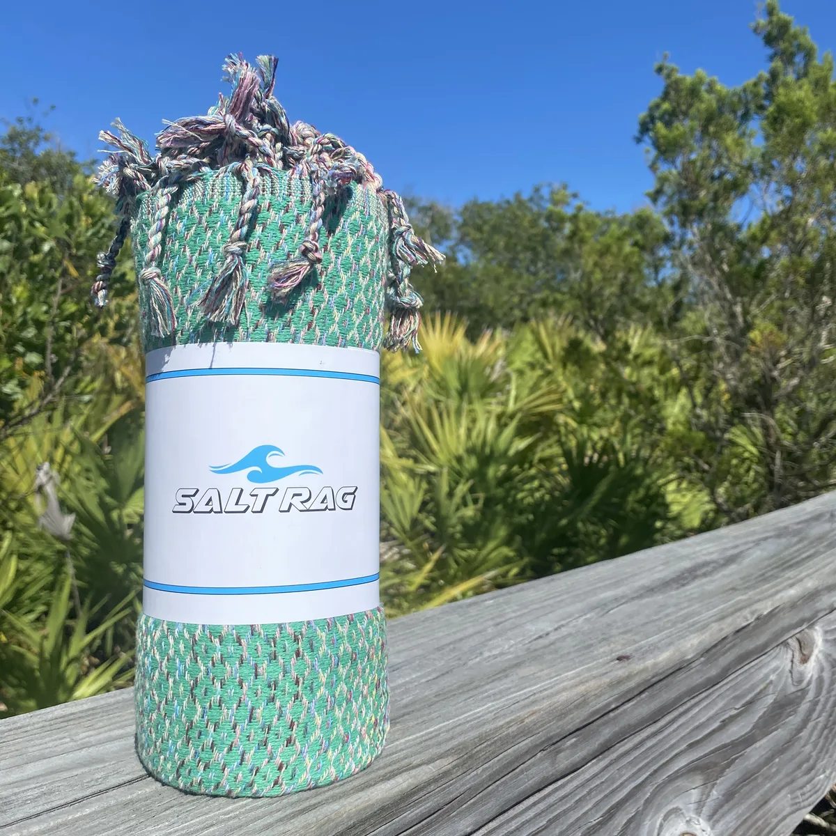 Green patterned Salt Rag rolled on a weathered coastal rail.