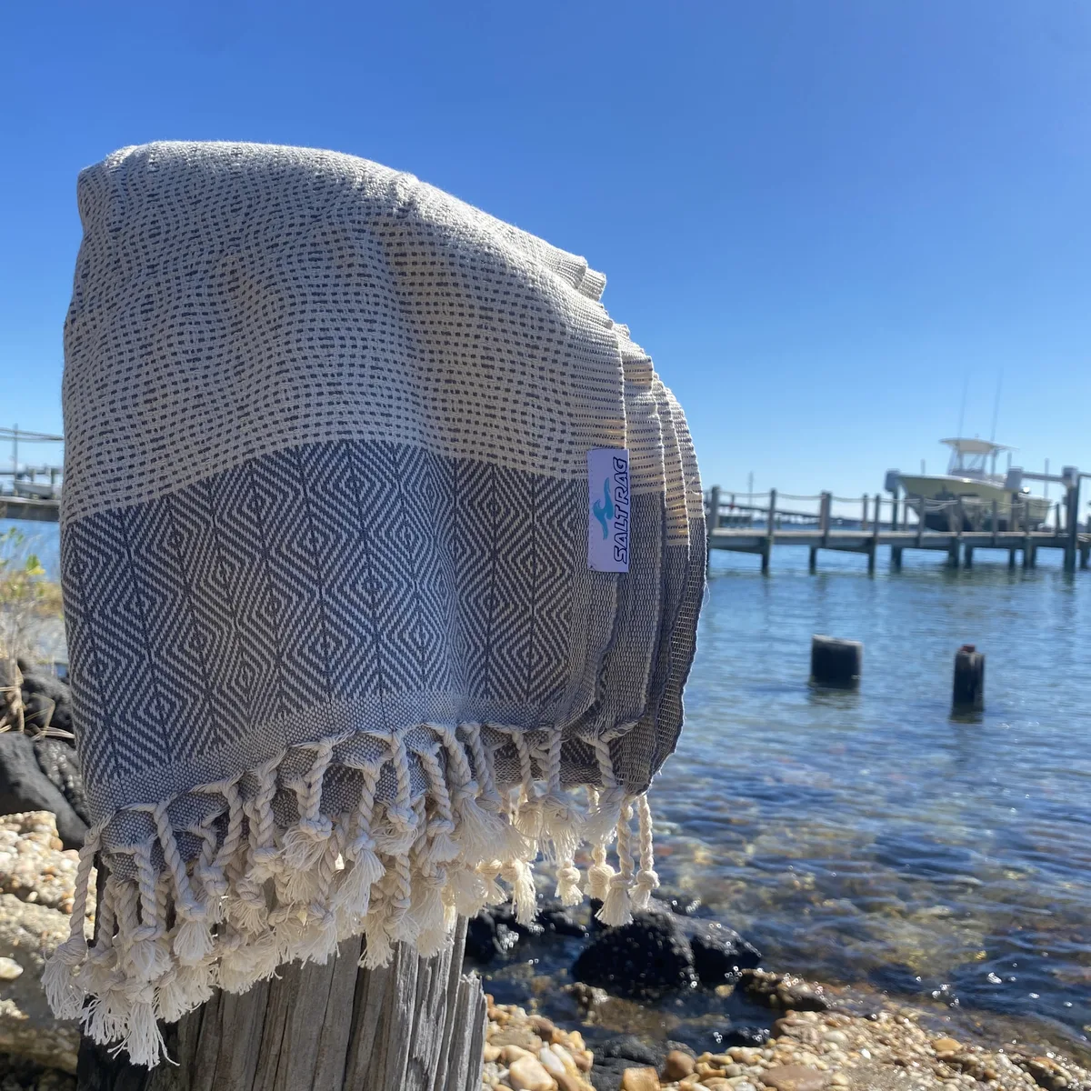 Pale striped Salt Rag draped beside a boat on the waterfront.