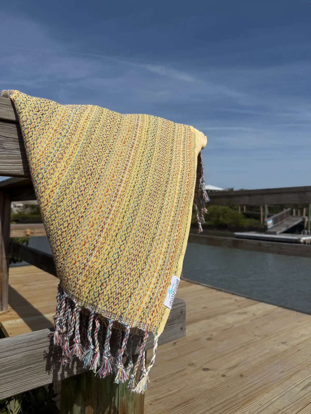 Yellow striped Salt Rag hanging over a waterfront rail.
