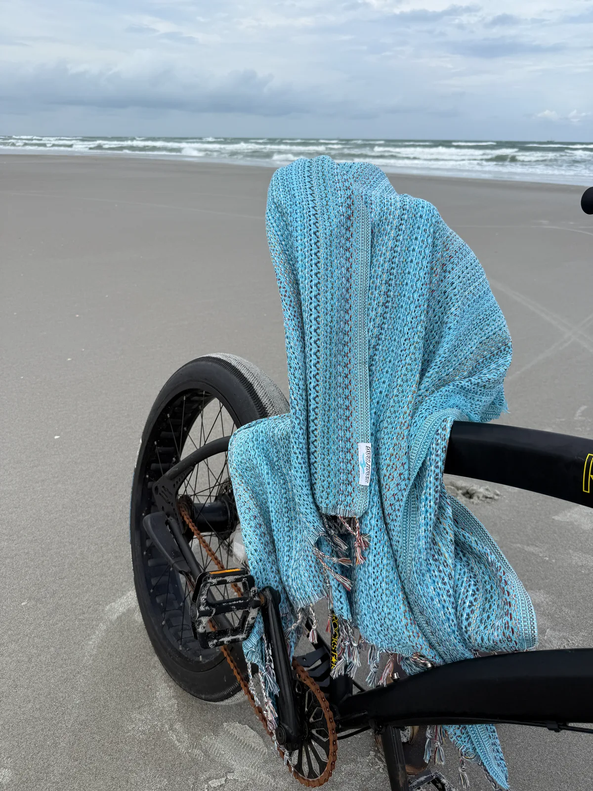 Blue patterned Salt Rag hanging over a bicycle on the beach.