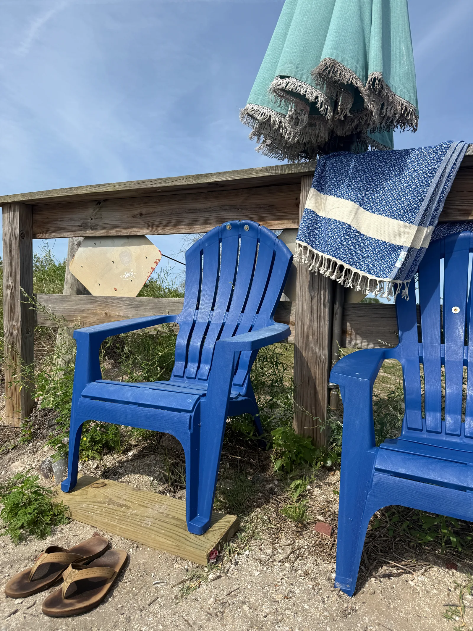 Blue outdoor Adirondack chairs beside a navy and cream Salt Rag draped over a waterfront rail.