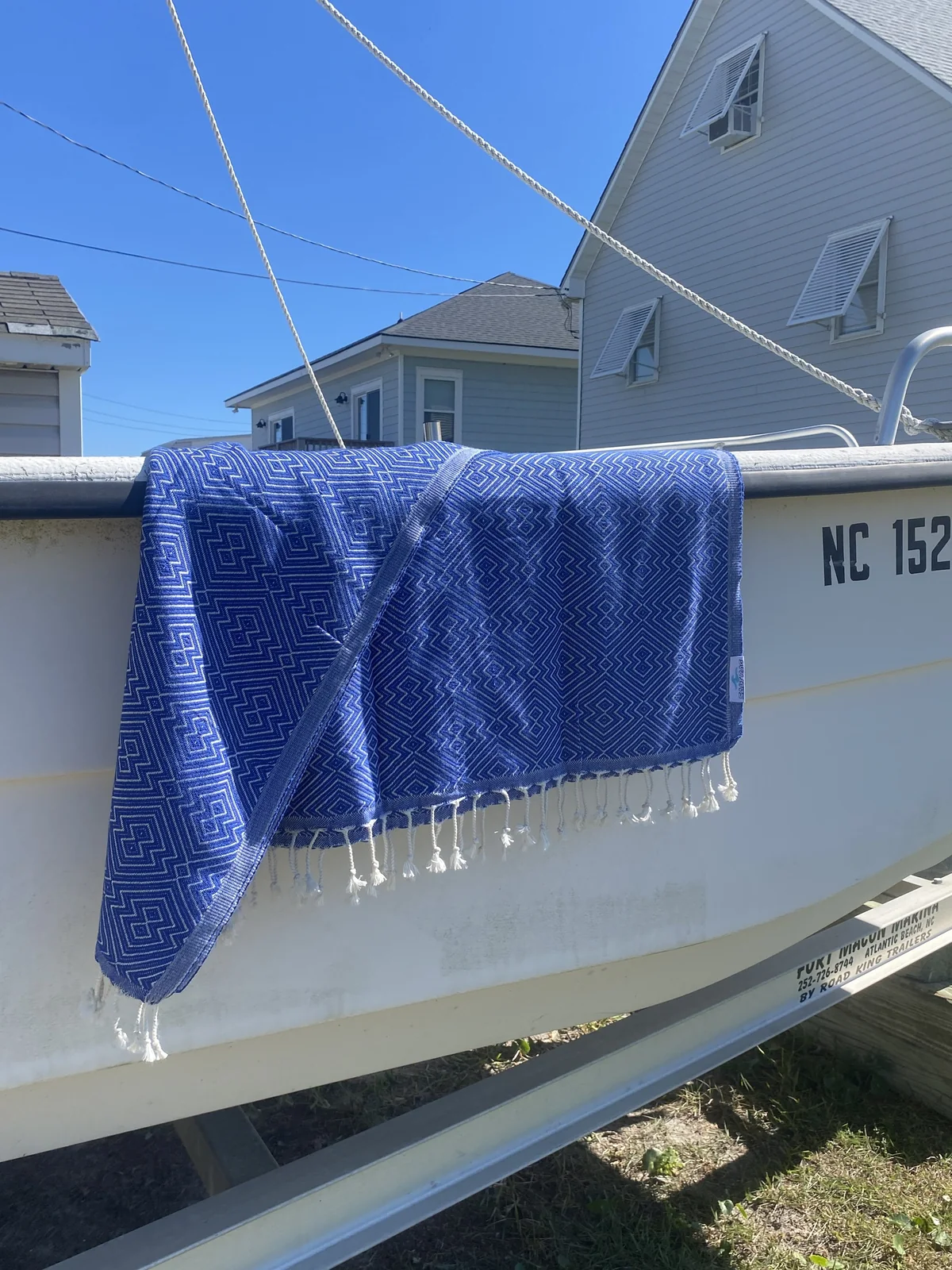 Blue patterned Rag draped over a boat rail with full fringe and marina context.